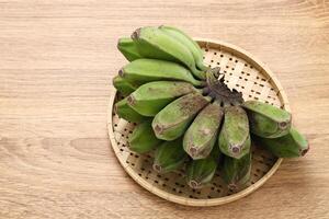 crudo kepok plátano o pisang kepok en de madera mesa foto