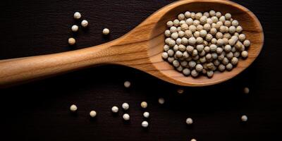 AI Generated White Peppercorn Pile In Wooden Spoon. Closeup Dry Pepper Heap. Top View Of Spicy Condiment On Dark Background. Organic Seasoning. photo