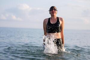 Woman swimmer jump out of sea water water with streaming splashes. photo