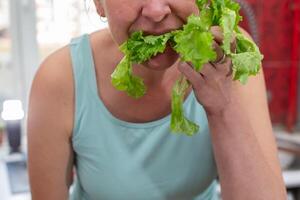A woman's hands hold a green salad. Eat food. photo