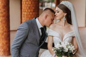 The bride is dressed in an elegant lush white wedding dress with a long veil and is ready for her groom. The first meeting of the bride and groom photo