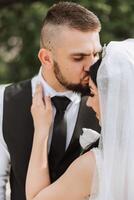 The groom kisses his bride on the temple against the background of beautiful nature on a summer day. Art. Selective focus. photo