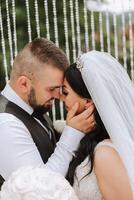 Close-up photo of a wedding couple looking each other in the eyes in nature. The bride and groom look each other in the middle of nature. Tenderness and love in the eyes.