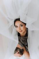 Portrait of the bride in the hotel room. A beautiful young girl is dressed in a white wedding dress. Modern wedding hairstyle. Natural makeup. photo