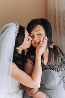 A beautiful and happy mother and her daughter, the bride, are standing next to each other. The best day for parents. Tender moments at the wedding. photo