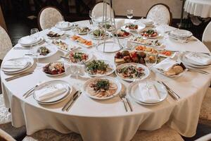 A view of wedding tables, attention to serving, with flower arrangements, expensive cutlery, plates with white napkins. photo