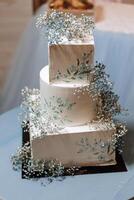 a three-tiered wedding cake decorated with flowers stands on a decorative stand. Decorative wedding cake. Beauty is in the details. photo