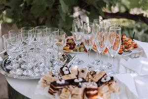 aire libre buffet mesa, emparedados en brochetas antes de el comienzo de el fiesta en contra el antecedentes de floración arboles en el jardín foto