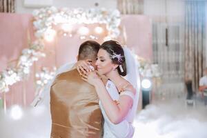 Wedding dance of the bride and groom. The first dance of the bride and groom in an elegant wedding hall with the use of heavy smoke and pyrotechnic lights, confetti. photo