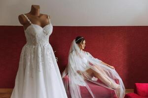 hermosa novia en blanco Boda vestir sentado en el cama en el Mañana. Moda disparo, hermosa mujer en un vendaje vestido. moda, glamour concepto foto