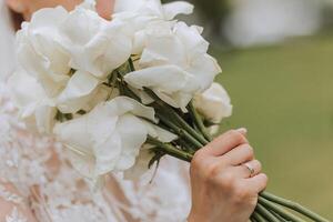 The bride is holding a wedding bouquet of white flowers roses, close-up photo. Wedding details. High quality photo