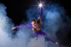 circo Actriz realiza el número en un hermosa fumar. manual equilibrio en bastones flexible niña cuerpo.rendimiento de un aire gimnasta en un circo foto