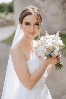 Beautiful bride with wedding flowers bouquet, attractive woman in wedding dress. Happy newlywed woman. Bride with wedding makeup and hairstyle. Smiling bride. Wedding day. Gorgeous bride. Marriage. photo