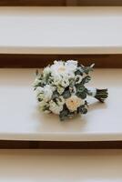 Boda ramo. blanco cortar rosas, verde semilla cabezas y hojas. verde tallos y blanco cinta y oro Boda anillos foto
