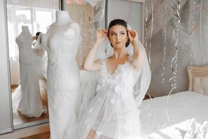 A beautiful bride is sitting in a dressing gown in the morning before the wedding ceremony in a hotel with a modern interior. Incredible hairstyle of the bride. Natural and modern makeup. photo