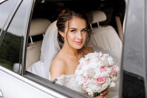 The bride looks out of the car window. Close-up portrait of a pretty shy bride in a car window. Bride smile emotions photo