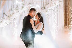 Wedding dance of the bride and groom. The first dance of the bride and groom in an elegant wedding hall with the use of heavy smoke and pyrotechnic lights, confetti. photo