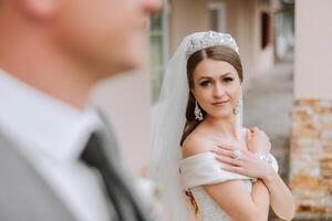 The bride is dressed in an elegant lush white wedding dress with a long veil and is ready for her groom. The first meeting of the bride and groom photo