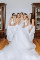 A beautiful bride and her bridesmaids are having fun in the morning. Wedding celebration. Happy girls at their best friend's wedding. A beautiful and elegant bride with her bridesmaids photo