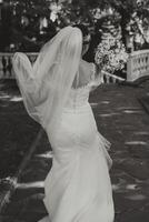 hermosa novia en un blanco Boda vestido. un joven novia niña es caminando en naturaleza en un verano día. verano boda. negro y blanco foto