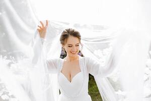 Beautiful bride in a dressing gown in the morning before the wedding ceremony. Incredible hairstyle of the bride. Natural and modern makeup. Portrait of a young bride in a dressing gown. photo