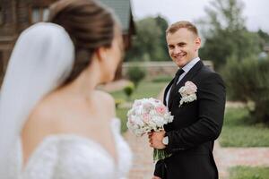 The bride is dressed in an elegant lush white wedding dress with a long veil and is ready for her groom. The first meeting of the bride and groom photo