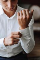 Business shirt. A man in a white shirt fastens the buttons. Young politician, male style, businessman buttoning shirt, male hands close-up, american, european businessman photo