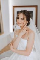 retrato de el novia en el hotel habitación. un hermosa joven niña es vestido en un blanco Boda vestido. moderno Boda peinado. natural constituir. foto