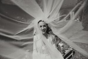 hermosa joven novia participación velo en blanco Boda vestido, retrato de morena novia en hotel habitación, Mañana antes de boda. foto