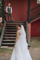 Beautiful sexy brunette bride in a white dress walking to the stairs, bride walk in nature. Wedding portrait. photo