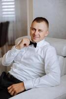 Portrait of a young groom at home before the wedding ceremony. A handsome man dressed in a classic suit. Male portrait. photo