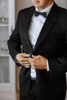 Man fastens the buttons. The groom in a suit. Close up. Man is buttoning his vest. Perfect to the last detail. Modern businessman. photo