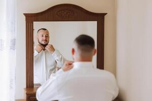 negocio camisa. un hombre en un blanco camisa sujeta el botones. joven político, masculino estilo, empresario abotonarse camisa, masculino manos de cerca, americano, europeo empresario foto