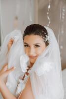 Beautiful bride in a dressing gown in the morning before the wedding ceremony. Incredible hairstyle of the bride. Natural and modern makeup. Portrait of a young bride in a dressing gown. photo