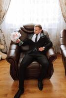 Portrait of a young groom at home before the wedding ceremony. A handsome man dressed in a classic suit. Male portrait. photo