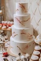 a four-tiered white wedding cake stands on a decorative stand. Decorative wedding cake. Beauty is in the details. photo