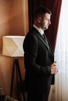 retrato de un joven novio a hogar antes de el Boda ceremonia. un hermoso hombre vestido en un clásico traje. masculino retrato. foto