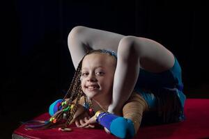 un niña con un flexible cuerpo. realiza un circo artista. circo gimnasta. equilibrio acto. el niño realiza un acrobático truco foto