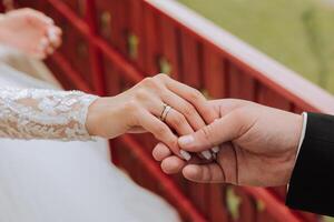 Groom holding bride's hand, cropped photo. Details at the wedding. Gold wedding rings on hands. High quality photo. photo