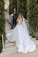 The bride is dressed in an elegant lush white wedding dress with a long veil and is ready for her groom. The first meeting of the bride and groom photo