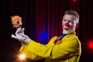 Circus clown performs number. A man in a clown outfit with a toy photo