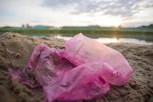 Cellophane package on the river bank. Environmental pollution.Garbage on the beach photo