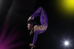 circo Actriz realiza el número en un hermosa fumar. manual equilibrio en bastones flexible niña cuerpo.rendimiento de un aire gimnasta en un circo foto