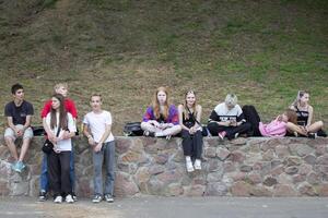 June 24, 2023. Belarusian city of Gomel, Central Park. A group of teenage boys and girls is sitting on the street. Adolescence. photo