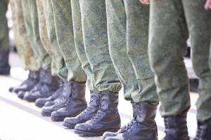 línea arriba soldados en protector ropa y botas. ellos son expedido a guerra o capacitación. foto