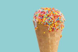 Ice cream cone close up. White ice cream scoop in a waffle cone on a blue background. Sweet dessert decorated with multicolored sprinkles photo