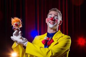 Circus clown performs number. A man in a clown outfit with a toy photo