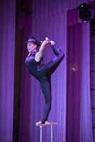 Acrobatic performance of the actress.Girl with a flexible body on a horizontal background.Balancing act photo