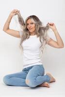Beautiful adult woman with long gray hair posing against gray background photo