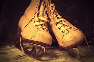 Vintage old skates, shabby and worn out on a snowy background in brown tinting. photo